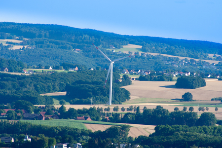 A windmill standing alone on a hill in Germany that produces electricity. Beautiful landscape and wind turbineの写真素材
