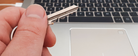 A key in a male hand on a laptop keyboard background