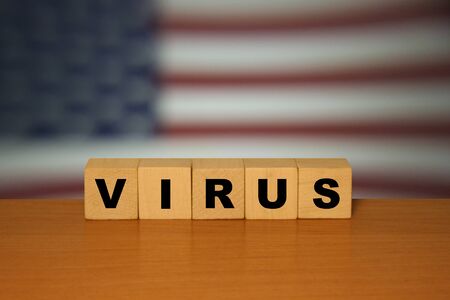 Virus message sign on a wooden desk on cube blocks with a USA flag background. Coronavirus concept.の写真素材