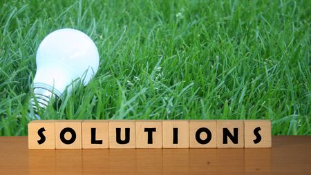 SOLUTIONS  message word on a wooden desk on cube blocks with a green nature background