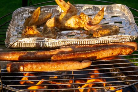 Delicious grilled meat over the coals on barbecue.  Chicken and sausages.