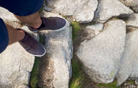 Low section of man on rock in mountains. Man shoe. Hiking adventure.の写真素材
