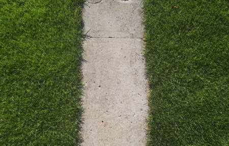 A symetric concrete path and beautiful green grass on the sides