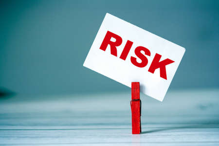 Reminder sticky note with clothes pin on table. Sticky note with word RISK. Danger conceptの写真素材