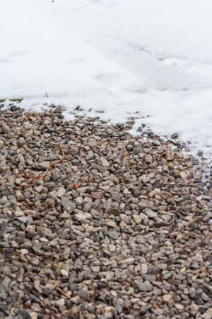 Small gravel road covered in snow texture. Winter pebble background. Dirty road. Fros morning. Snowy land closeupの写真素材