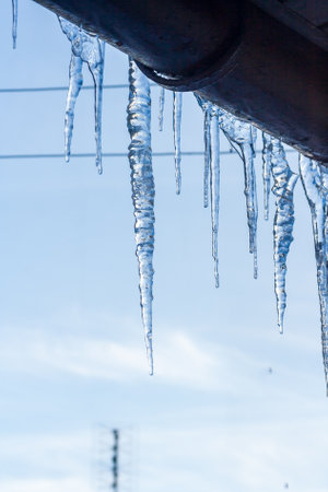 Icicles hanging from roof of house. Winter concept. Closeup danger icicles. Frozen climate pattern. Frost winter seasonの写真素材