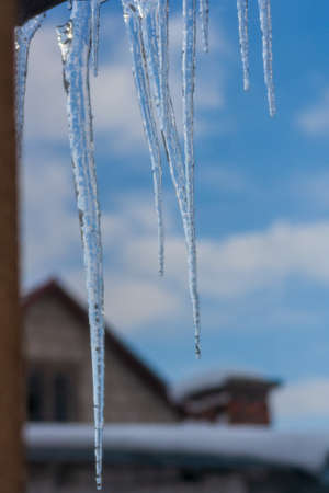 Long and dangerous icicles hanging from roof of house. Winter season concept. Frost and snow weather...