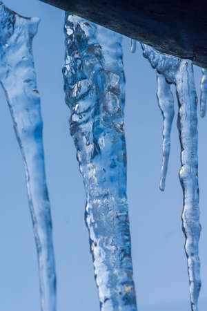 Closeup icicles background. Icicles hanging down from a roof. Cold winter weather, winter season...
