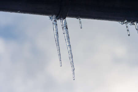 Icicles hanging from roof of house. Winter concept. Closeup danger icicles. Frozen climate pattern....