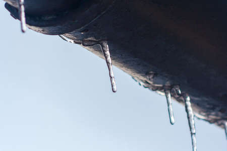 Icicles hanging from roof of house. Winter concept. Closeup danger icicles. Frozen climate pattern. Frost winter seasonの写真素材
