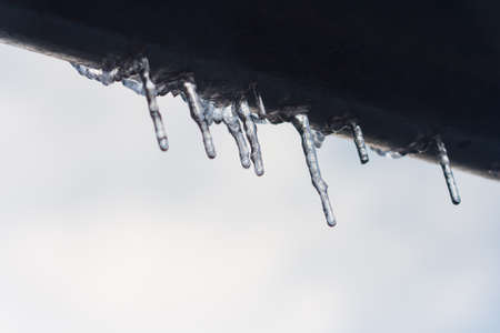 Icicles hanging from roof of house. Winter concept. Closeup danger icicles. Frozen climate pattern. Frost winter seasonの写真素材