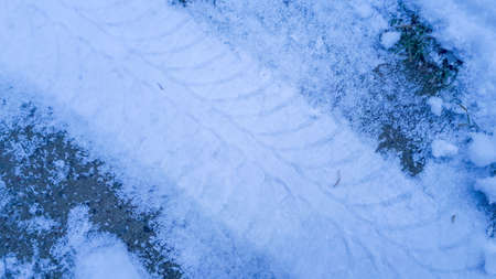 Fresh tire track in the snow. Wheel tracks on the road covered with snowの写真素材