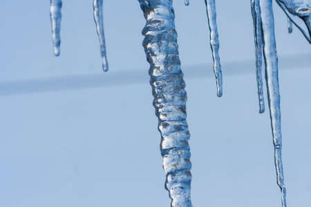 Closeup icicles background. Icicles hanging down from a roof. Cold winter weather, winter season conceptの写真素材