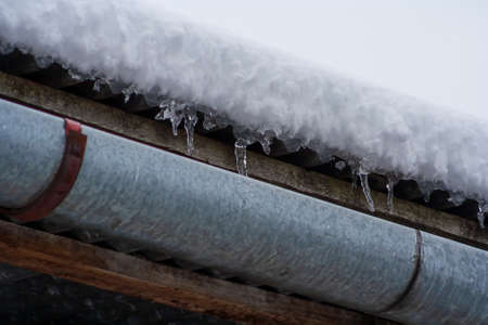 Icicles hanging from roof of house. Dangerous icicles concept. Melting snow. Change weather
