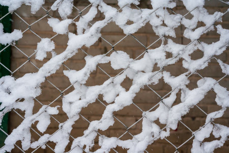 Snow covered metal fence in winter. Heavy snowfall, Blizzard. Closeup fence with snow