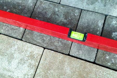 Laying paving stones. Measuring the slope with a spirit level. Laying paving stones on sand. A...