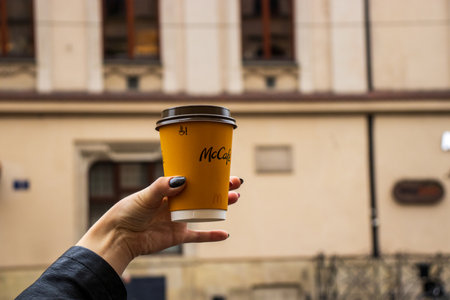 Cracow Poland, October 2, 2022: Cup of McDonald's coffee in a woman hand. Cup of McCafe coffee from McDonalds fast food restaurant.のeditorial素材