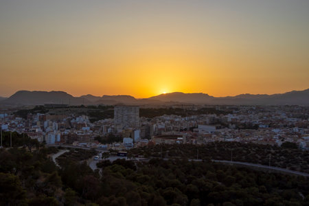 Stunning sunset over Alicante with cityscape in foreground. The vibrant colors create a serene...