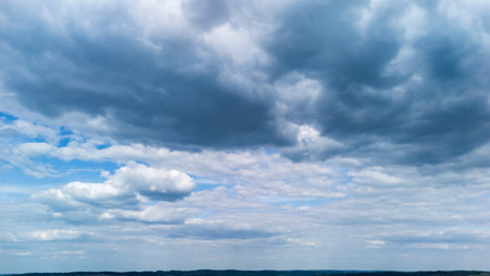 Vast sky filled with dramatic clouds casting shadows over the landscape below showcasing a serene...