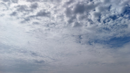 Expansive sky filled with soft billowing clouds blending shades of gray and blue creating a serene...