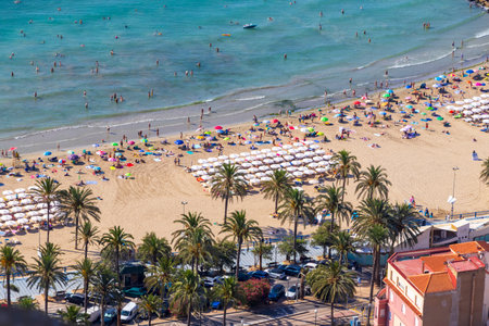 Aerial view of Playa de San Juan beach in Alicante featuring sunbathers colorful umbrellas and clear blue waters during a sunny summer day. Perfect for holiday promotions.の写真素材