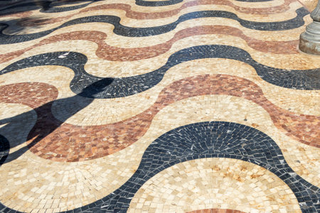 An artistic pattern of wavy cobblestones creates a visually engaging surface scene located in a sunny urban environment perfect for decorative design and architecture.の写真素材