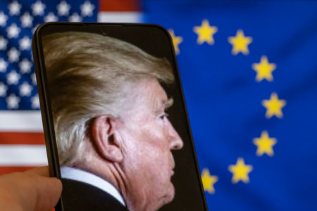 Warsaw Poland - September 17 2025: A close-up of Donald Trump on a smartphone with American and European flags in the background symbolizing international relations.のeditorial素材