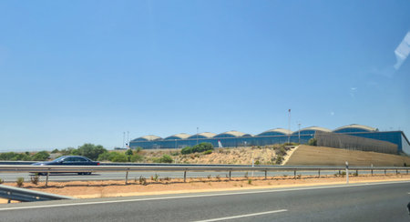 Alicante Spain - July 17 2025: View of Alicante Airport from the roadway showcasing modern architecture against a clear blue sky. Ideal for travel and transportation themes.のeditorial素材