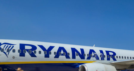 Alicante Spain - July 17 2025: A close-up view of a Ryanair airplane parked on the tarmac showcasing its iconic blue and yellow branding against a clear blue sky.のeditorial素材