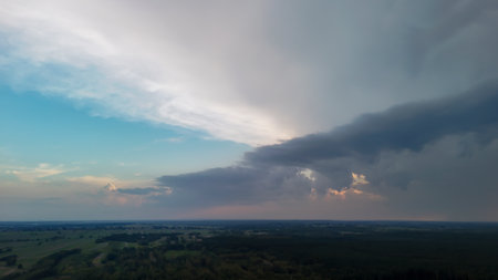 Dramatic sky over a vast landscape showcasing a blend of blue and gray hues as clouds gather above...