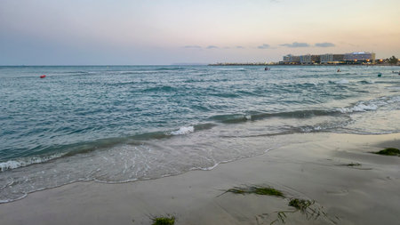Alicante Spain - July 12 2025: Waves gently lap against the sandy shore of a picturesque beach...