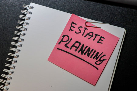 A close-up view of a notebook with a pink sticky note that reads ESTATE PLANNING representing the...