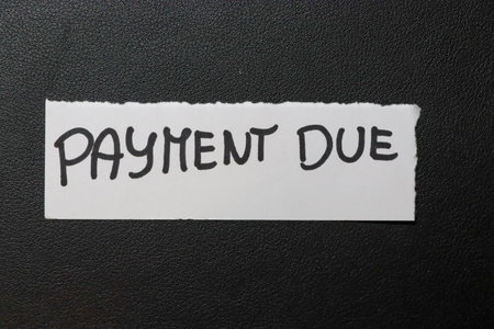 Illustrative note reading Payment Due on textured black background indicating financial obligations...