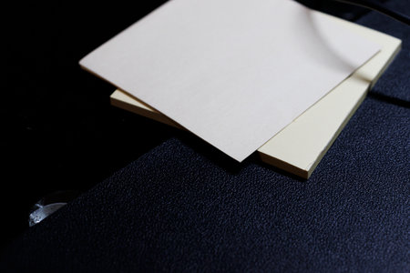 Close-up of blank sticky notes on a textured black surface ideal for office use and organization. Plain design perfect for notes and reminders.の写真素材