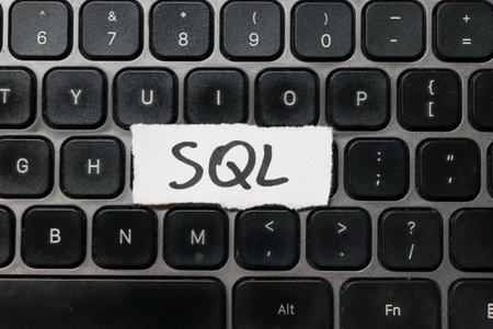 Handwritten SQL on a white paper strip placed on a modern black keyboard. This image symbolizes programming database management and coding practices in technology.の写真素材