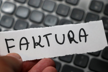 A close-up view of a hand holding a piece of paper placed on a computer keyboard illustrating the theme of finance and paperwork.の写真素材