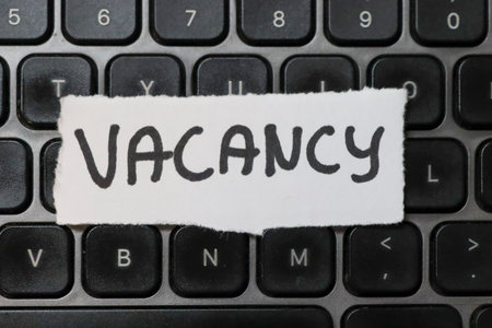 Close-up view of a laptop keyboard with a paper sign reading VACANCY symbolizing job opportunities and recruitment. Ideal for business-related content.の写真素材