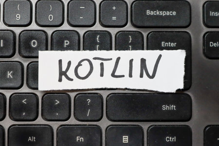Handwritten word KOTLIN on a white paper strip placed on a black keyboard symbolizing programming...
