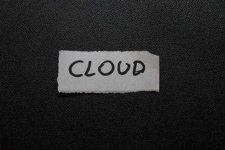 The word CLOUD handwritten on a piece of white paper contrasting against a dark background. This image signifies digital or weather concepts invoking creativity and imagination.の写真素材