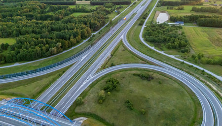 Aerial view of a complex highway interchange surrounded by lush greenery showcasing modern...