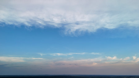 Vast blue sky with soft clouds creating a serene landscape at sunset. Ideal for nature-themed projects or backgrounds evoking tranquility and openness.の写真素材