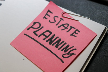 A close-up of a pink sticky note labeled ESTATE PLANNING pinned to a notebook symbolizing the importance of organizing and managing ones estate and finances.の写真素材