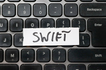 A handwritten note displaying the word SWIFT placed on a black keyboard symbolizing speed and efficiency in technology or communication ideal for business contexts.の写真素材