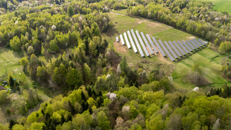 Aerial view of a solar farm surrounded by lush green forests showcasing renewable energy initiatives...