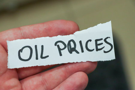 Handwritten note showing the phrase Oil Prices held in a hand representing the importance of oil economics and market trends in todays financial discussions.の写真素材