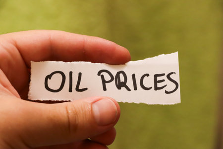 A hand holding a handwritten note that reads Oil Prices. This image symbolizes economic factors affecting the energy market with potential implications for industries worldwide.の写真素材