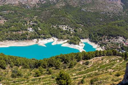 Stunning aerial view of turquoise lake surrounded by lush greenery and mountainous terrain in Guadalest Spain. A picturesque landscape perfect for outdoor activities and relaxation.の写真素材