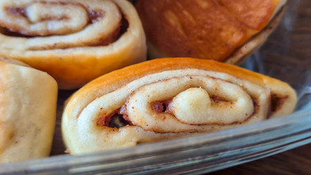 Close-up of freshly baked cinnamon rolls with a golden brown top showing the rolled pastry texture. Ideal for food photography or baking-related content.の写真素材