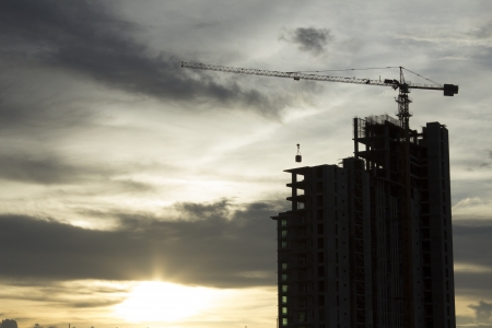 Building crane and building under construction against Sunsetの写真素材