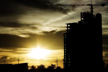 Building crane and building under construction against Sunsetの写真素材